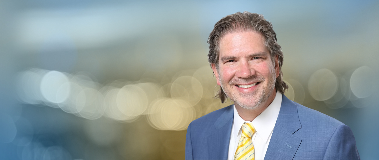 Professional headshot of Travis R. Hollifield against a blurred background